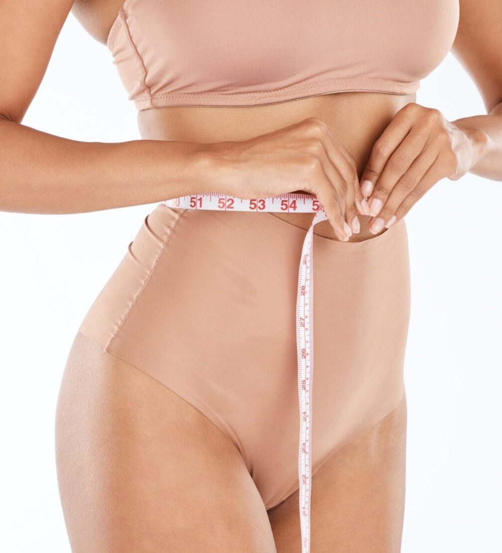 Tape, fitness body and woman isolated on a white background for lose weight or tummy tuck in underw