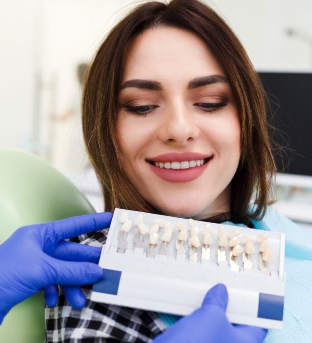 Dentist and his patient choose a tone of veneers. Dentistry doctor shows a palette with shades for teeth